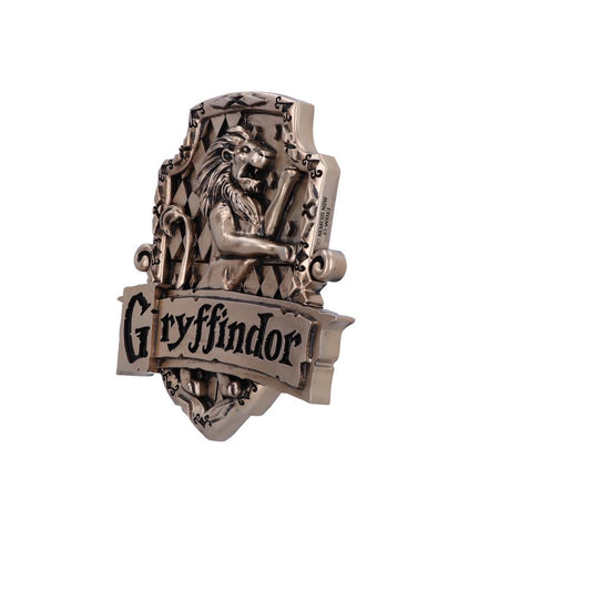 A metallic Gryffindor crest displays a lion, surrounded by scrollwork, with "Gryffindor" written prominently. The crest features a heraldic shield design, set against a plain white background.