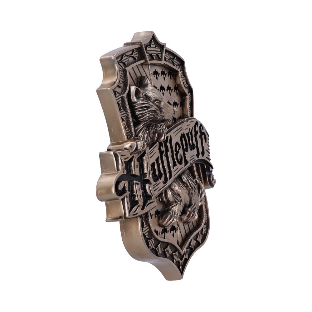A detailed metal emblem features a badger with the word "Hufflepuff" inscribed across it. It’s shaped like a shield, highlighting intricate patterns and a polished finish.