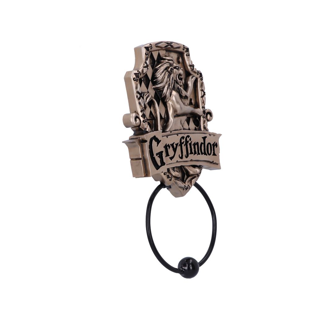 A metal door knocker with a lion emblem is mounted on a decorative plaque. Below the lion, "Gryffindor" is inscribed. A ring hangs below, set against a plain white background.