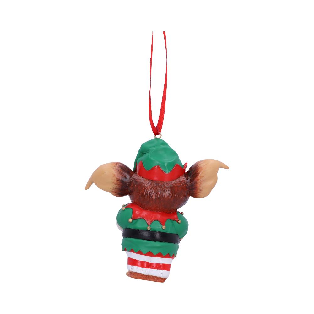 A whimsical ornament resembling a creature wearing a festive green and red outfit hangs by a red ribbon, set against a plain white background.