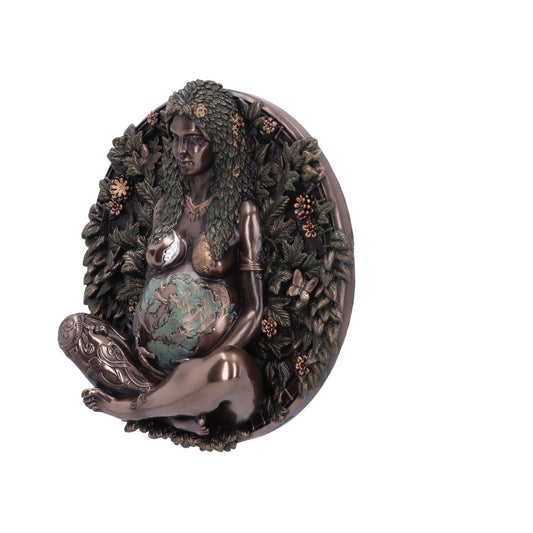 A bronze figurine depicts a seated goddess cradling the Earth, surrounded by foliage. The piece is a wall hanging.
