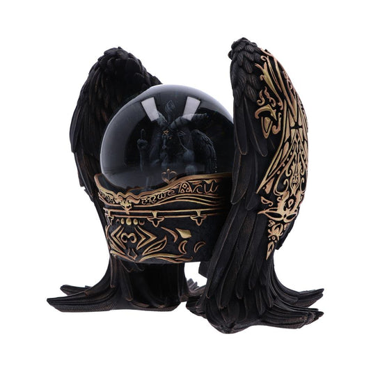 A snow globe, containing a demonic figure, sits within a sculpted, black raven's wing frame, adorned with gold detailing.