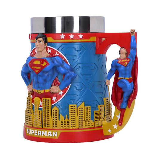 A mug featuring a 3D Superman figure stands atop a city skyline, with a flying Superman as the handle. Blue background with "SUPERMAN" text and star decorations.