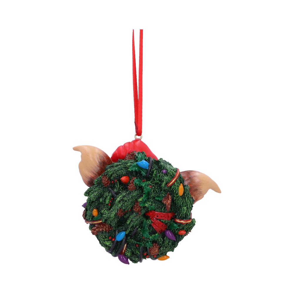 A round, ornament resembling a creature with large ears and a red hat is decorated with colorful lights and greenery, suspended by a red ribbon, against a plain white background.