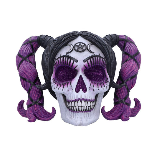A skull adorned with pink pigtails and glittery purple eyesockets, featuring a crescent and pentagram symbol on its forehead, against a plain white background.