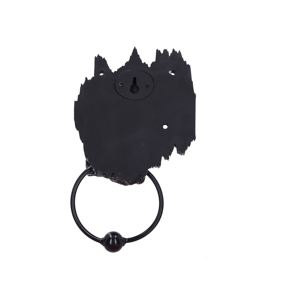 A weathered black metal door knocker with an irregularly shaped backplate and a circular ring, set against a plain white background.