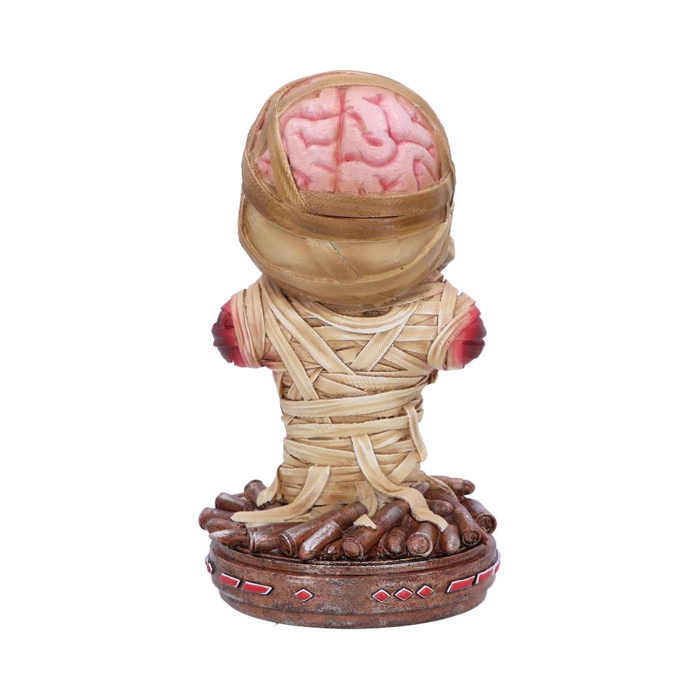 A small figure features a brain encased in glass, wrapped with straps, sitting on a circular, textured base adorned with red geometric designs, creating a surreal appearance in a minimal setting.