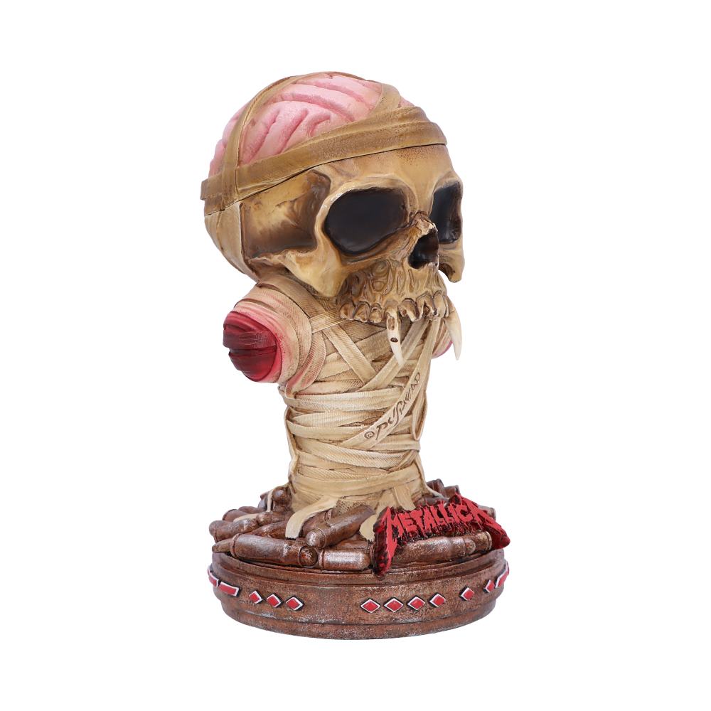 Skull figurine wrapped in bandages, displaying exposed brain and fangs, stands on a circular base surrounded by spikes. The base features red "Metallica" text.