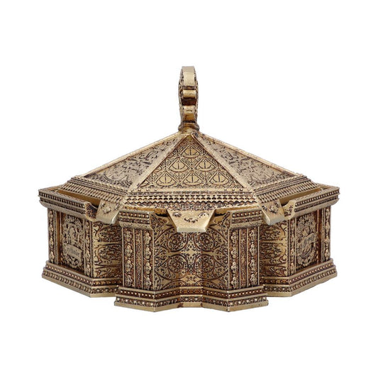 A hexagonal, ornate golden box with a pointed lid and intricate engravings sits against a plain white background, featuring a looped handle on top for opening.