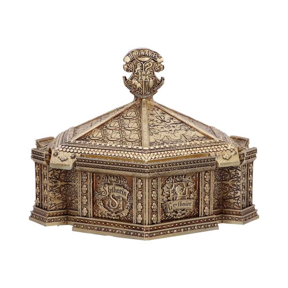 A golden, ornate box features intricate carvings with "Hogwarts," "Slytherin," and "Gryffindor" text. The lid is pyramid-shaped with decorative patterns and a prominent emblem on top.
