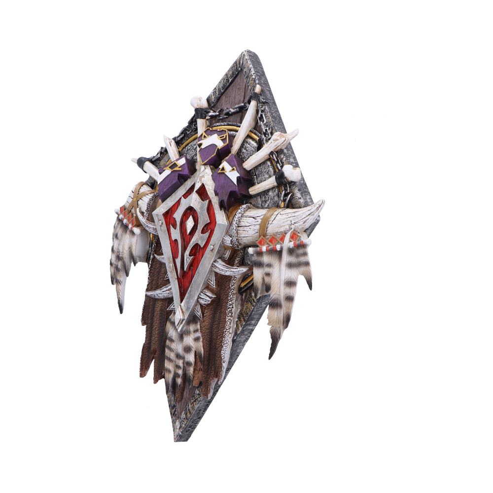 Decorative shield adorned with feathers, bones, purple patches, and a red symbol, mounted on a wooden backboard. The design is ornate, suggesting a fantasy or tribal theme.