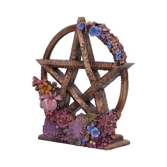 A pentacle, adorned with flowers, stands on a base. The pentacle is wooden-looking and features carvings. The background is white.