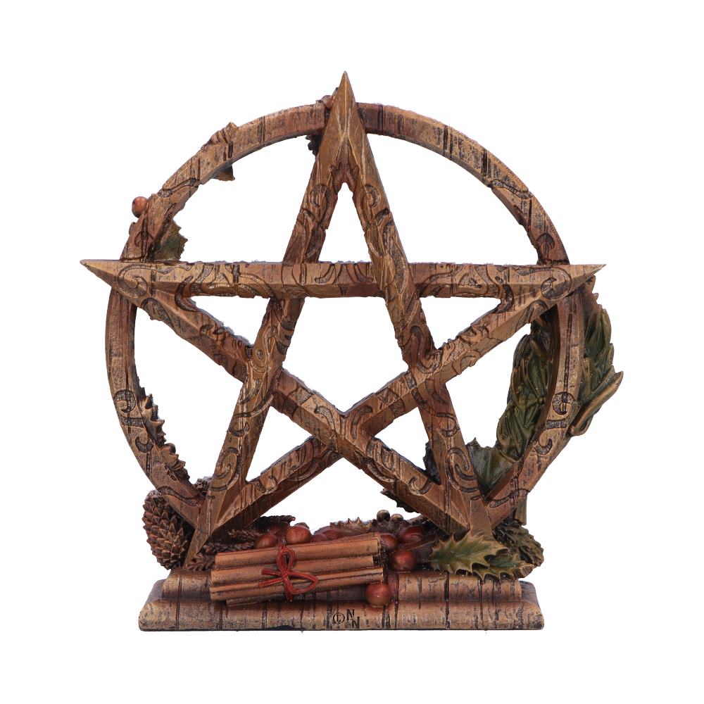 A pentacle sits on a base; it is made of wood and decorated with autumnal motifs. Cinnamon sticks and berries are arranged at its base.