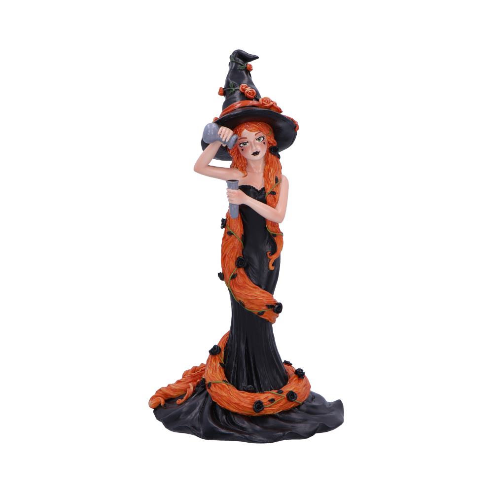 A witch figurine pours potion; her long orange hair flows down her black dress, adorned with black roses; the setting is a plain white background.