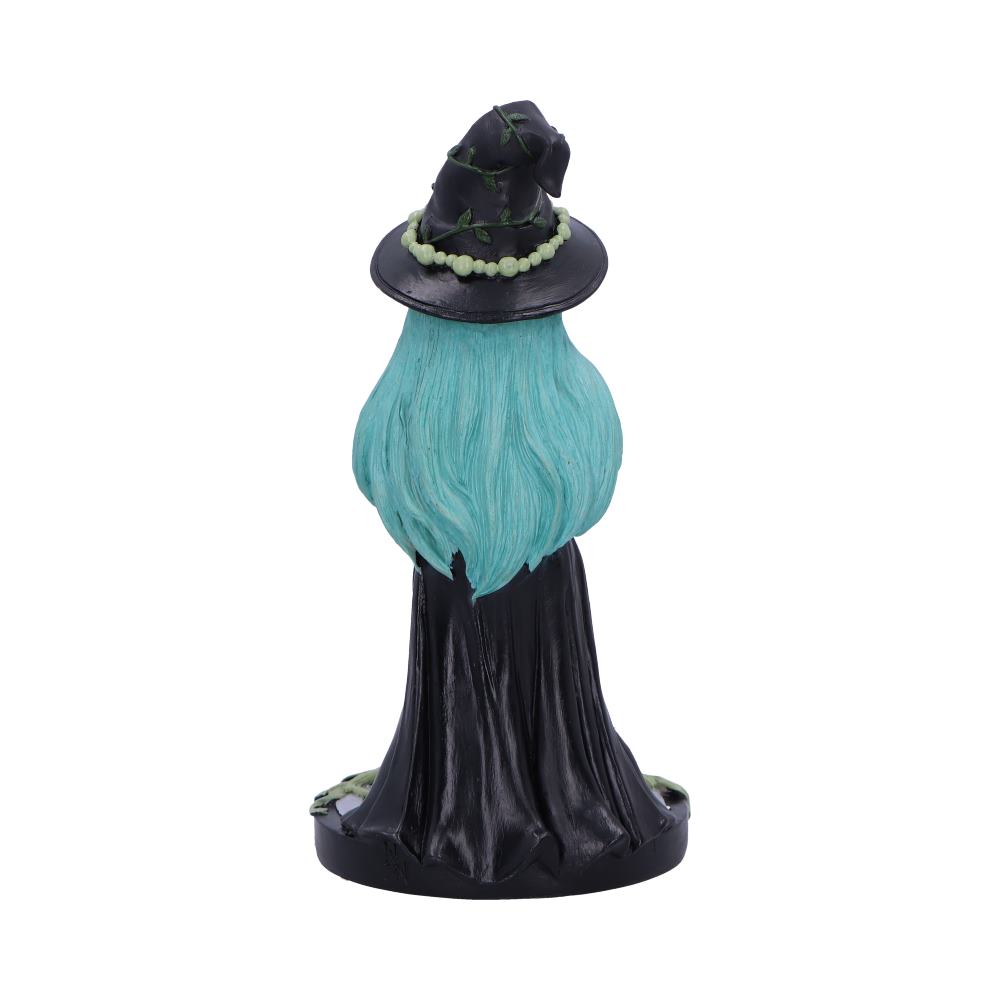 A witch figurine sits; she has teal hair, a black hat with vines, and a black cloak. The figurine is on a circular base.