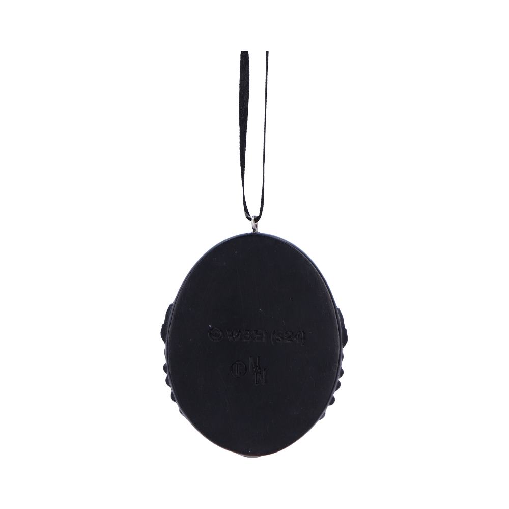 A black oval object hanging by a string, displaying the text "© WBEI (s24)" and "ON" in a plain, well-lit background.