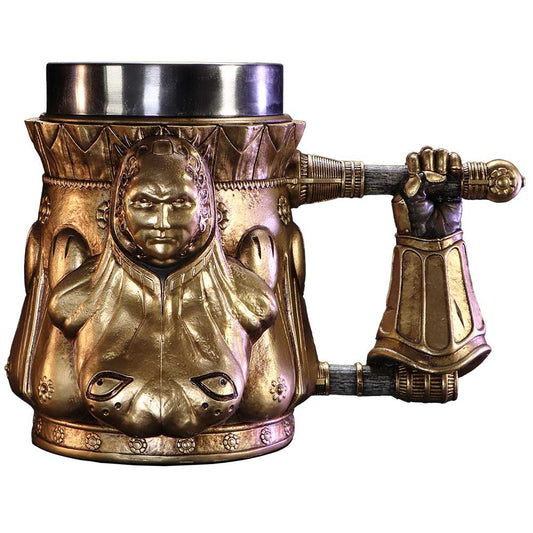 A gold mug features a sculpted, armoured figure with a serious expression as decoration. Its handle is a detailed gloved hand gripping a pole, set against a plain background.