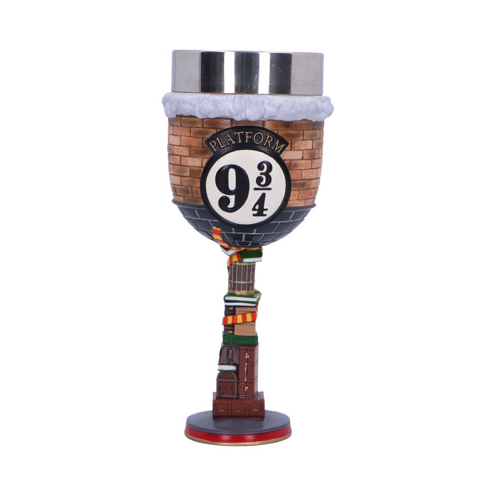 A goblet features a brick design with "Platform 9 3/4" text, topped with a metallic rim. The stem mimics luggage with a colorful scarf, set against a plain background.