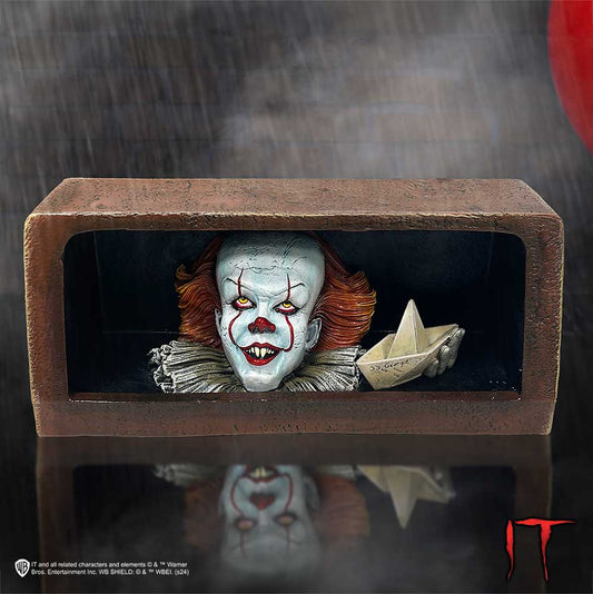 A creepy clown emerges from a dark gutter, holding a paper boat labeled "SS Georgie." It's rainy, with a red balloon partially visible, creating an ominous atmosphere.
Text: "IT and all related characters and elements © & ™ Warner Bros. Entertainment Inc. WB SHIELD: © & ™ WBEI. (s24)"