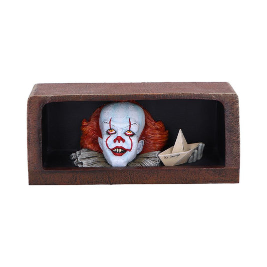 Clown head with red hair and face paint emerges from a dark box, holding a paper boat labeled "SS George" in its hand.