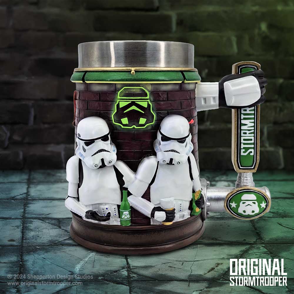 A novelty mug designed as a bar scene with two white-armored figures, holding drinks, against a brick-patterned backdrop. Text: "STORMTROOPER," "© 2024 Shepperton Design Studios," "www.originalstormtrooper.com," "ORIGINAL STORMTROOPER."