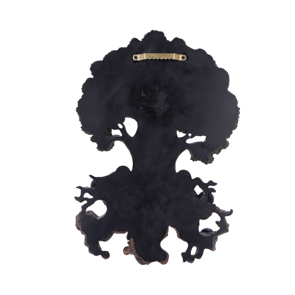 A dark, tree-shaped wall hanging, featuring a carved design, hangs against a white background. It has a brass hanger on the back.