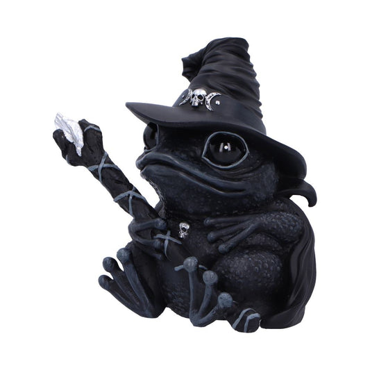 A black frog figurine, wearing a witch's hat and holding a staff, sits against a white background.