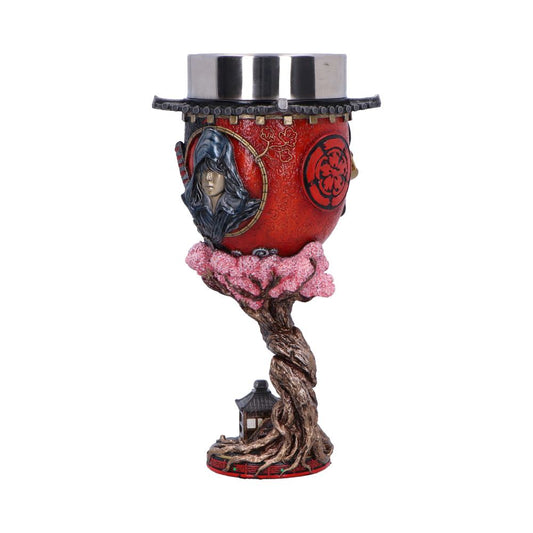 A detailed, decorative chalice features a red, embossed exterior depicting a hooded figure and symbols. It is supported by a twisted, tree-like stem with pink blossoms and a small pagoda at the base.