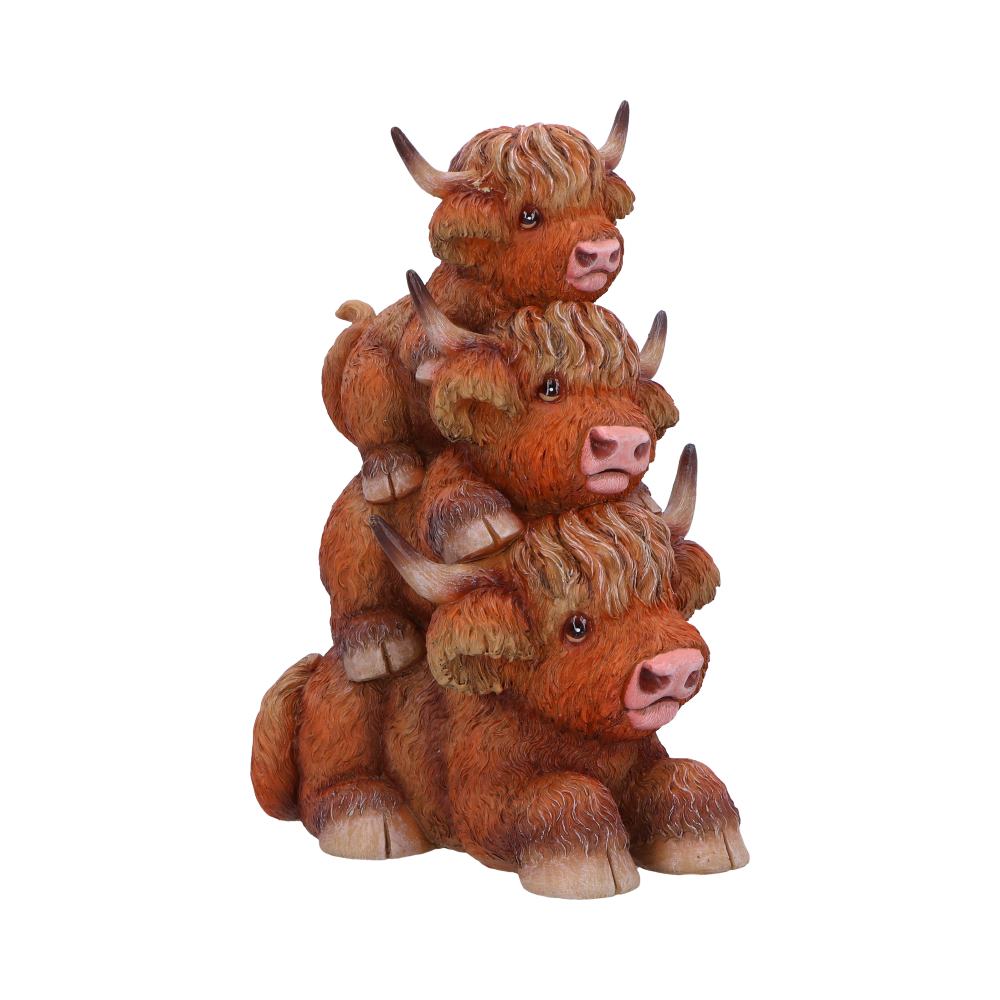Three small, brown, fluffy cow figurines are stacked on top of each other. The cows have big eyes and horns, with detailed fur texture. The background is plain white.