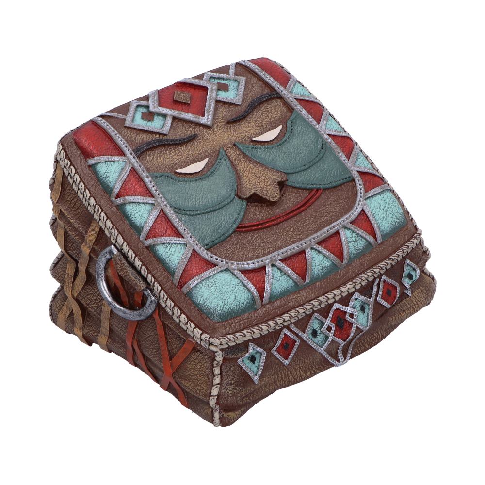 A decorative, book-shaped box features a stylized face with closed eyes and a serene expression. It is adorned with geometric patterns in turquoise, red, and brown hues.