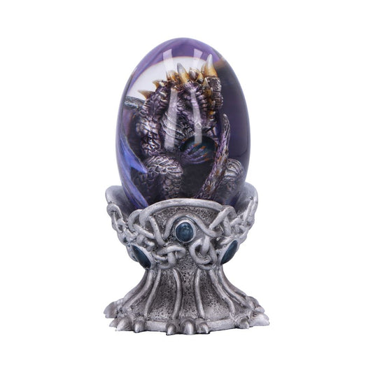 A sculpted dragon curled inside a transparent purple egg rests on an ornate, silver stand with blue gemstones, resembling a mythical or fantasy-themed artifact.