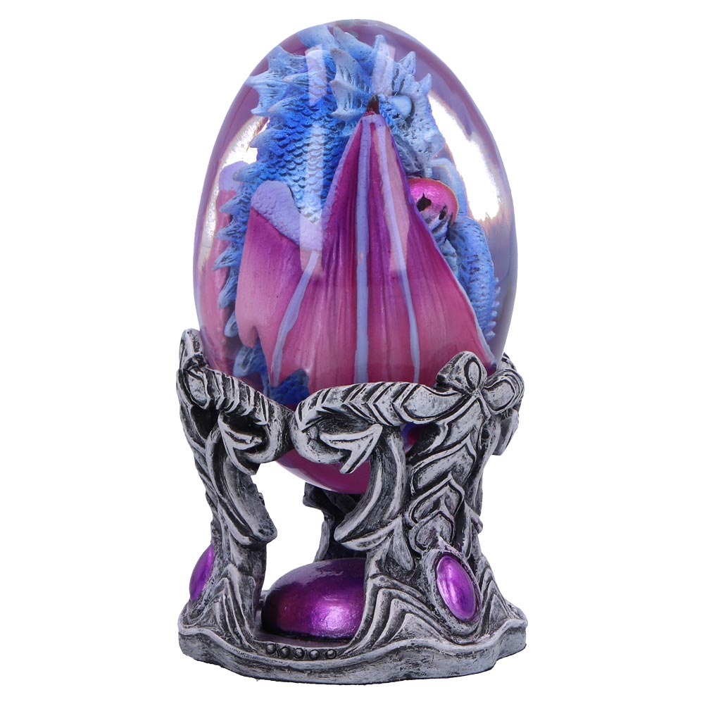 A blue and pink dragon figurine encased in a clear egg rests on an ornate, silver stand decorated with purple gems, creating a mystical and decorative scene.