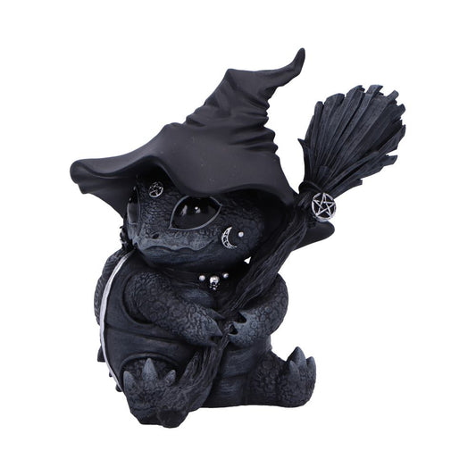 A small, dark-colored dragon wears a witch's hat and holds a broom with a pentacle charm, sitting calmly against a white background. The dragon has decorative moon and star accents.