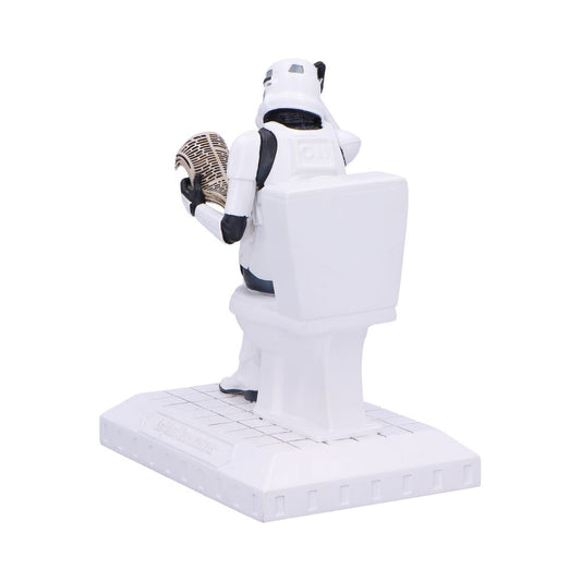 Plastic Stormtrooper figure sits on a toilet reading a folded newspaper while mounted on a small tiled display base against a plain white background.