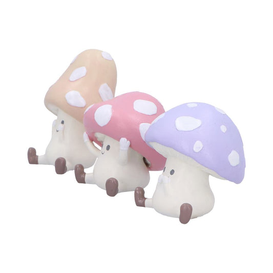 Three cartoon mushroom figurines sit in a row, each with small faces and raised arms, pastel beige, pink, and lavender caps against a plain white background.