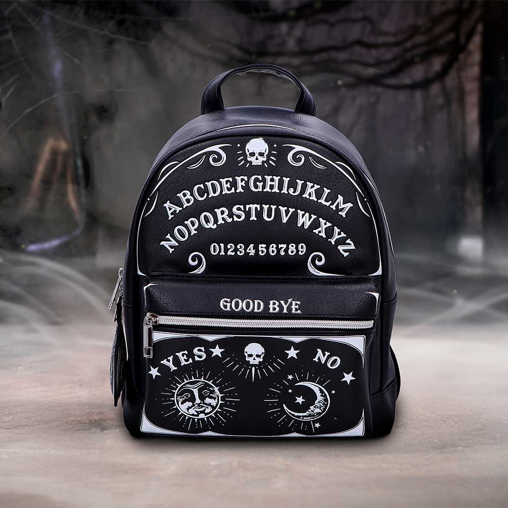 Black mini backpack sits on a foggy floor before blurred trees displaying Ouija-style graphics; text: ABCDEFGHIJKLM NOPQRSTUVWXYZ 0123456789 GOOD BYE YES NO