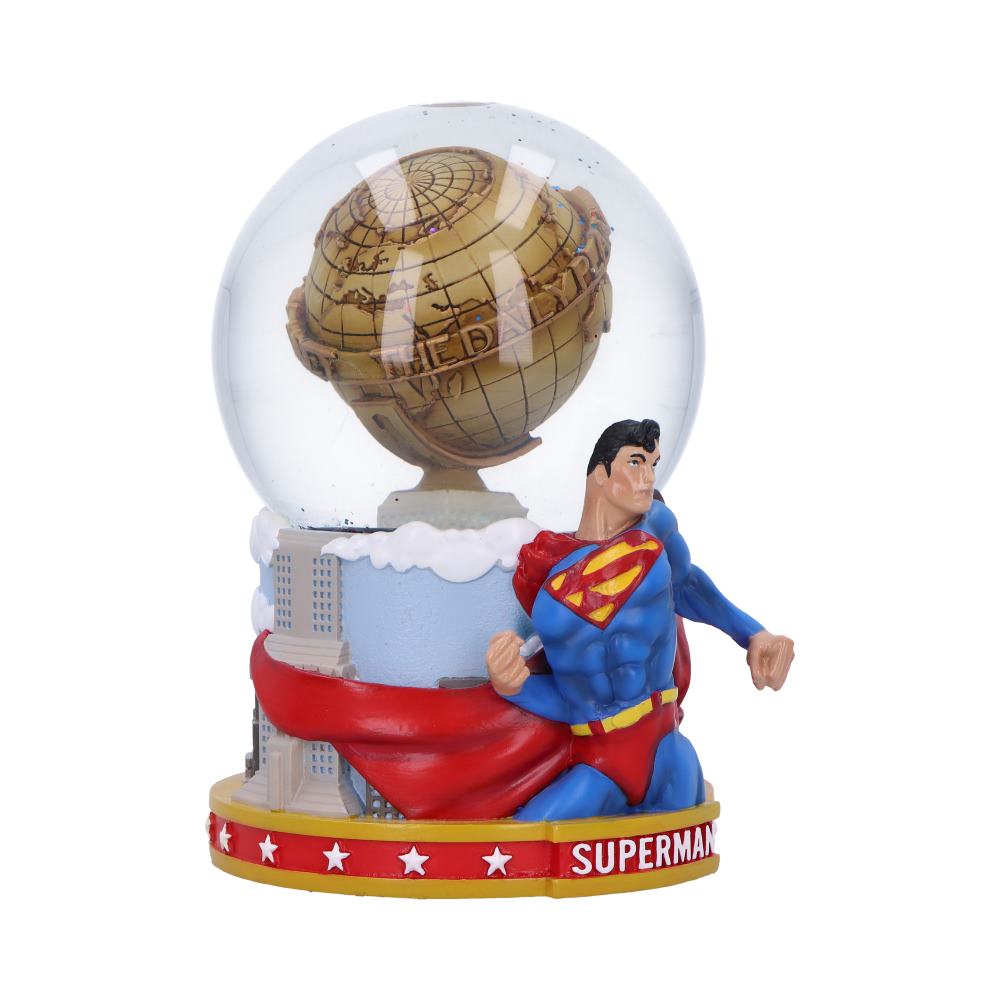 Superman figurine kneels with cape billowing beside a glass globe atop a miniature city skyline base, text on base reads SUPERMAN