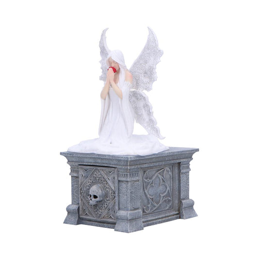 A white-winged female angel statue kneels holding a red rose to her face atop an ornate gray stone pedestal decorated with carved skull and floral motifs against a plain background.