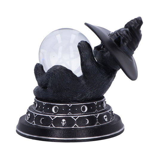 Black cat figurine wearing a witch hat cradles a clear crystal ball, lying on its back atop an ornate base decorated with moon phases and skull motifs on a white background.