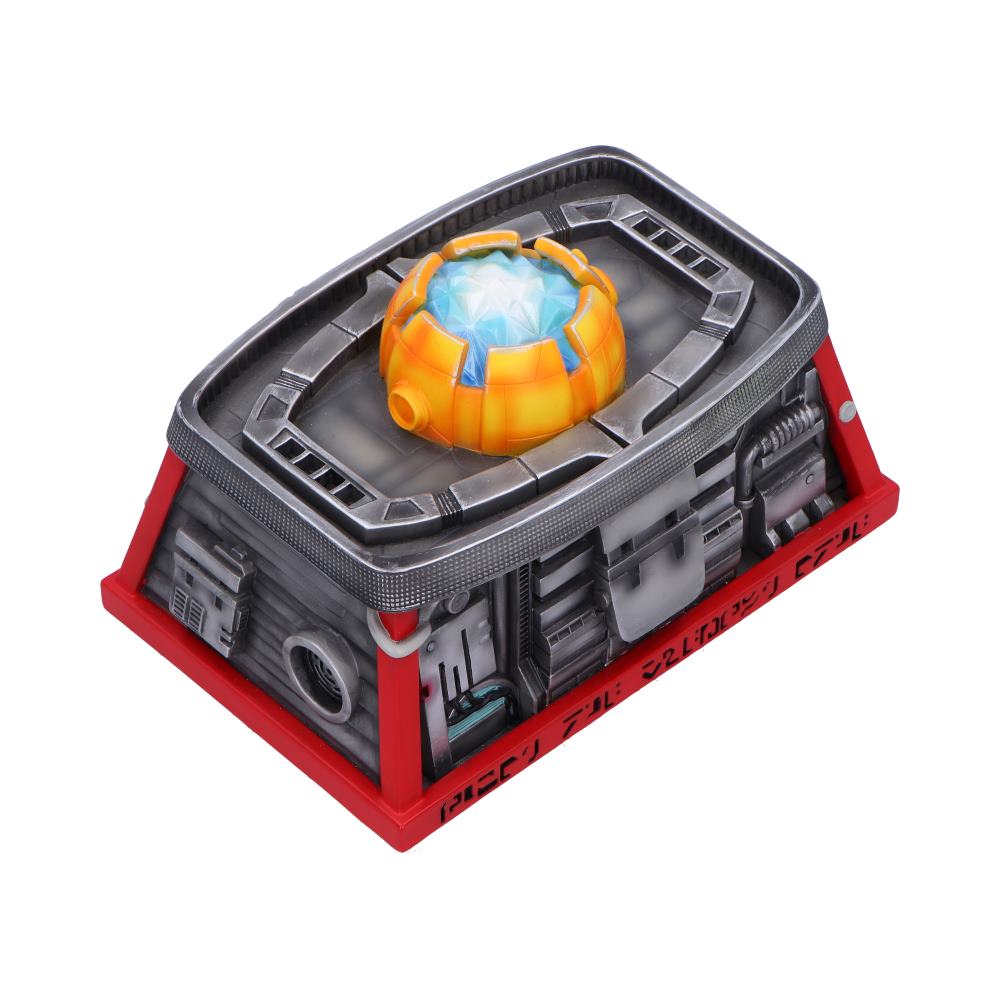Futuristic rectangular crate holds a glowing blue orb encased in an orange shell recessed on its metallic top, surrounded by mechanical details and a red base with small stylized black glyphs unreadable on a white background.