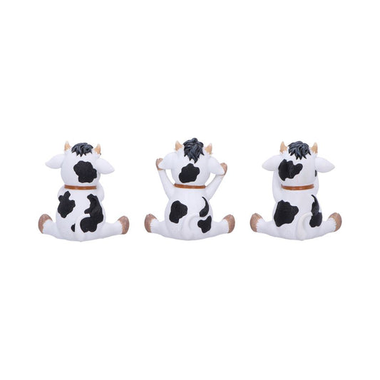 Three small white-and-black cow figurines sit side by side, middle one raising its front legs toward its head, all shown from the rear on a plain white background.