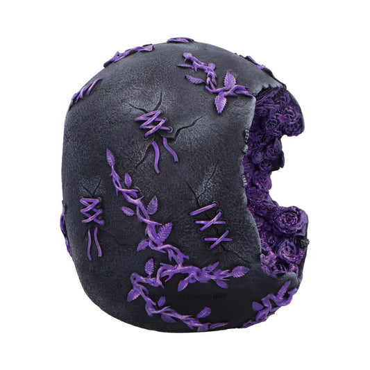Black ornamental skull decorated with purple vines and stitched laces, one side hollowed to reveal clustered purple roses, set against a white background; text: © NEMESIS NOW