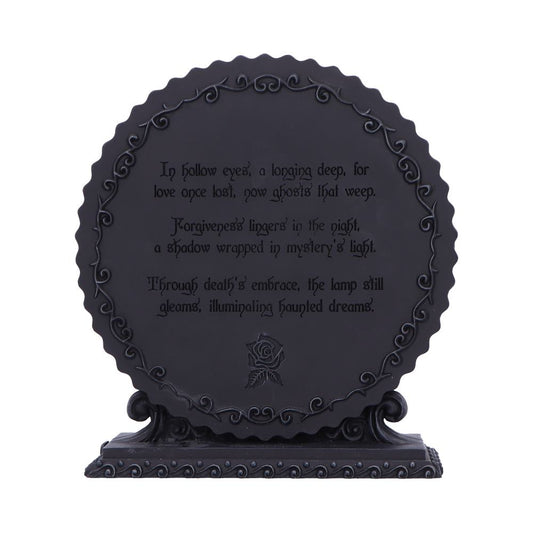 A round black decorative plaque displays a gothic poem reading "In hollow eyes, a longing deep, for love once lost, now ghosts that weep. Forgiveness lingers in the night, a shadow wrapped in mystery's light. Through death's embrace, the lamp still gleams, illuminating haunted dreams." on an ornate base against a white background.
