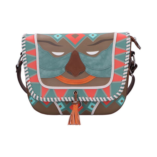 A teal coral and brown saddlebag purse sits centered, featuring a stylized face on the stitched flap with white whipstitch trim and an orange tassel, photographed on a white background