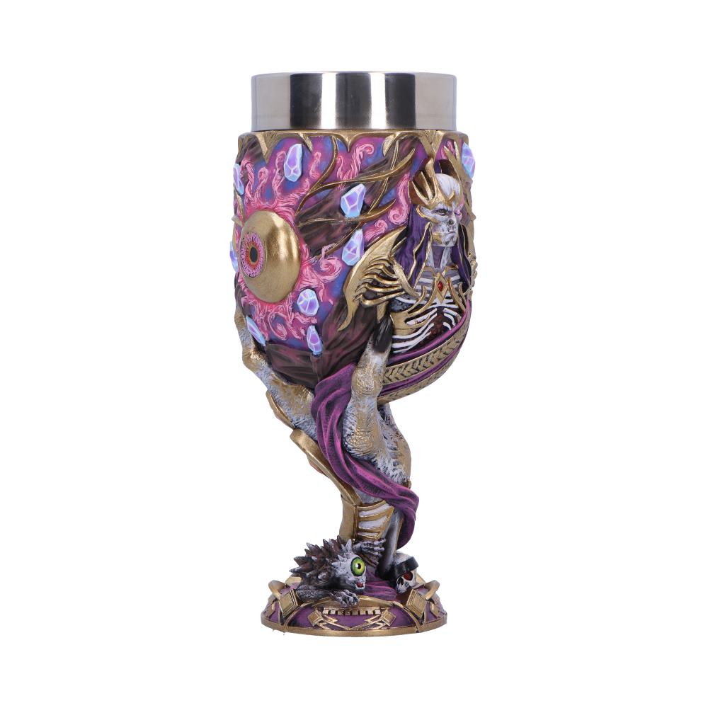 Ornate chalice cradled by twisted skeletal arms, featuring a horned skull, pink crystal clusters and a central golden eye, perched on a spiky creature base against a white studio background.