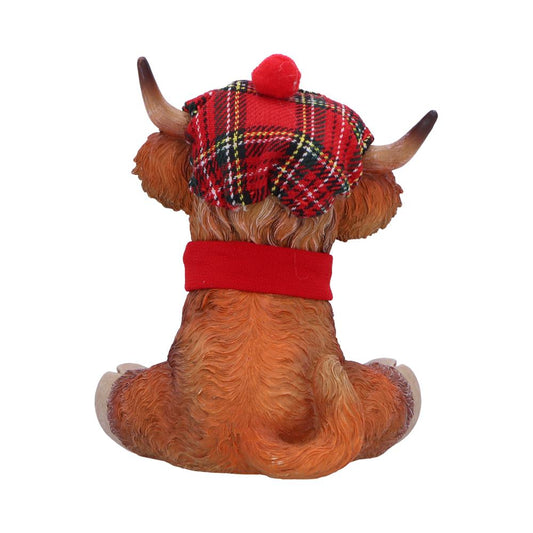 Highland cow figurine sits facing away, wearing a red tartan tam with pompom and a red collar on a plain white background.