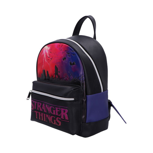 Backpack features a red and purple stormy silhouette scene with bats and figures, black body with purple side panels, front pocket labeled STRANGER THINGS, photographed on a white background.