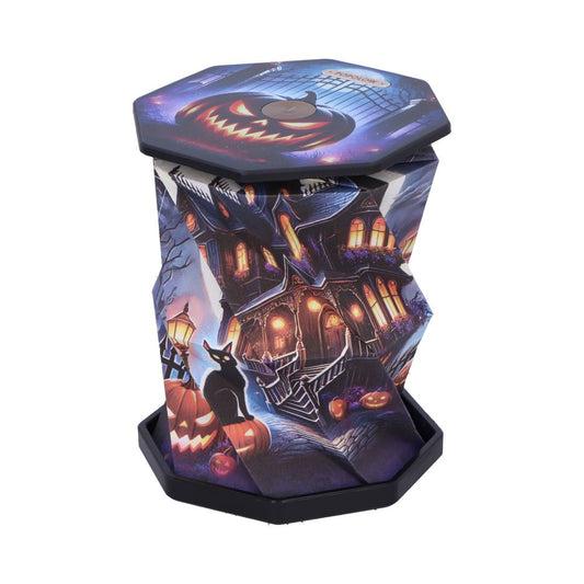 Octagonal Halloween lantern displays a glowing jack-o'-lantern face and haunted house scene; it folds into a short tower perched on a black base surrounded by carved pumpkins and a black cat.