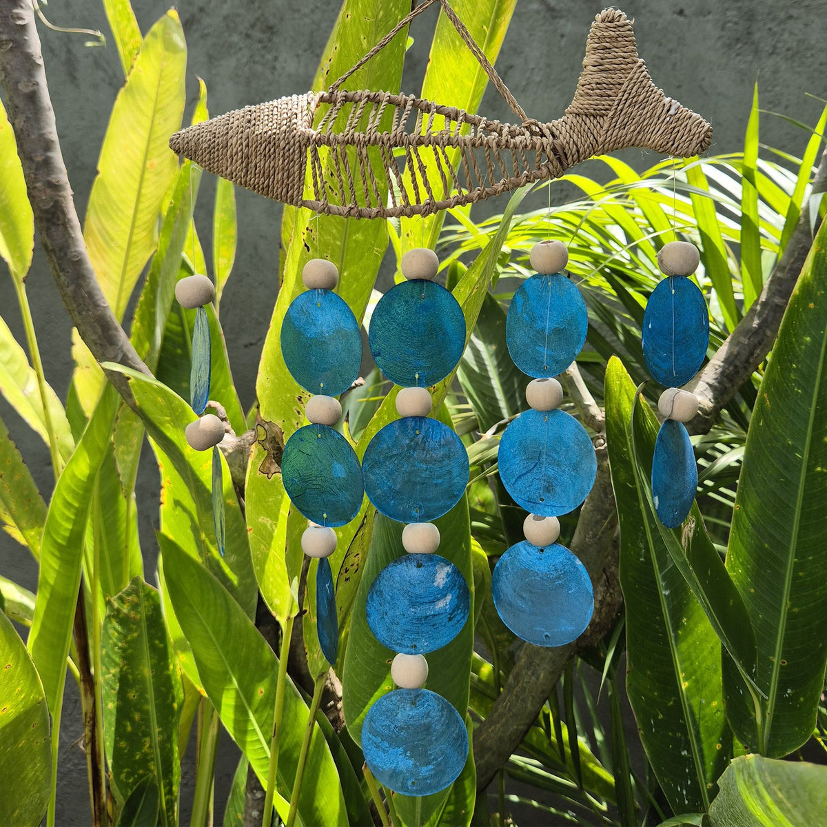 Handmade woven string fish windchime with blue Capiz shell drops.