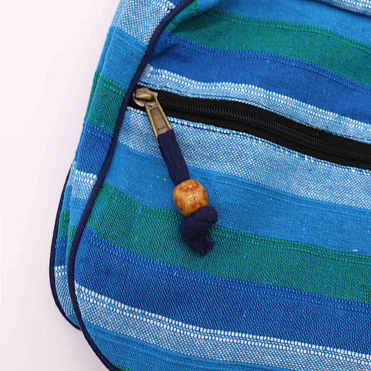 Blue and green striped fabric pouch with a brass zipper; a navy fabric pull with a wooden bead hangs from the zipper against a white background.